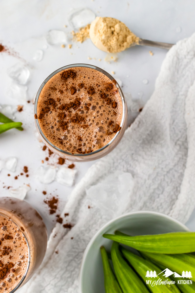 chocolate peanut butter milkshakes in glasses with bowl of okra and peanut flour on spoon