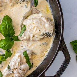 creamy basil chicken with cream sauce and fresh basil in cast iron skillet
