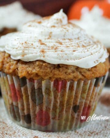 pumpkin cupcake with polka dot wrapper and cream cheese frosting with a sprinkle of cinnamon