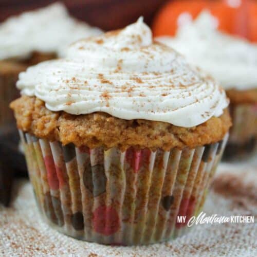 pumpkin cupcake with polka dot wrapper and cream cheese frosting with a sprinkle of cinnamon