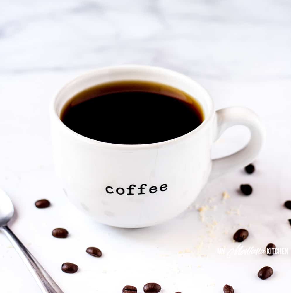 white cup with black coffee, spoon and coffee beans