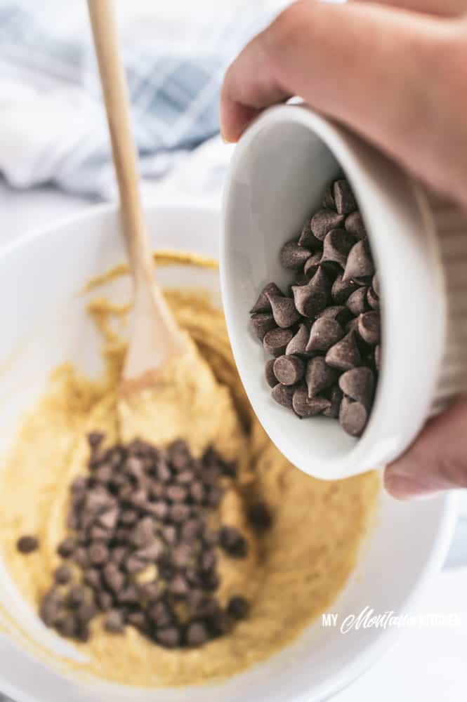 adding chocolate chips to cookie dough in mixing bowl