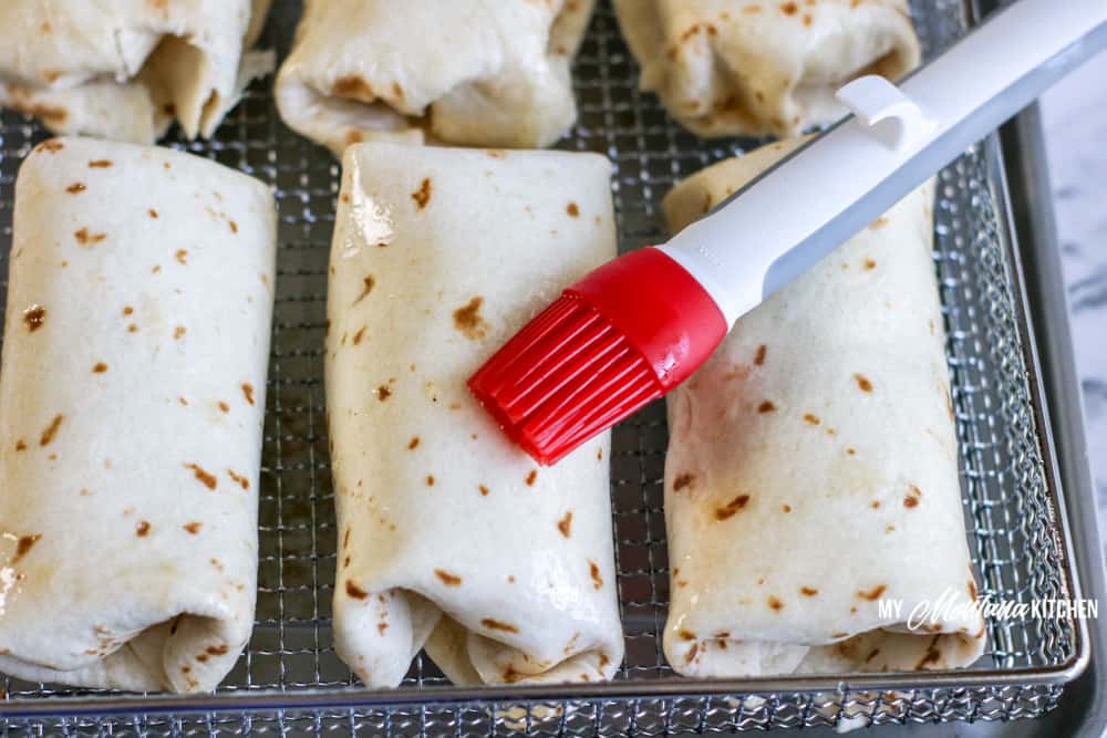 chimichangas in pan with basting brush and butter