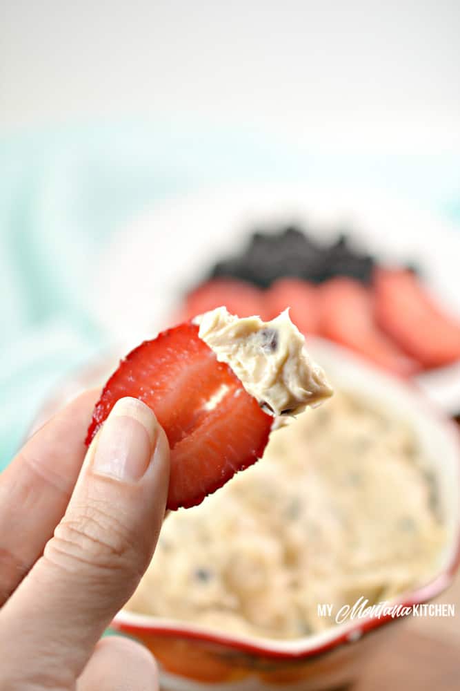 hand holding sliced strawberry with fruit dip