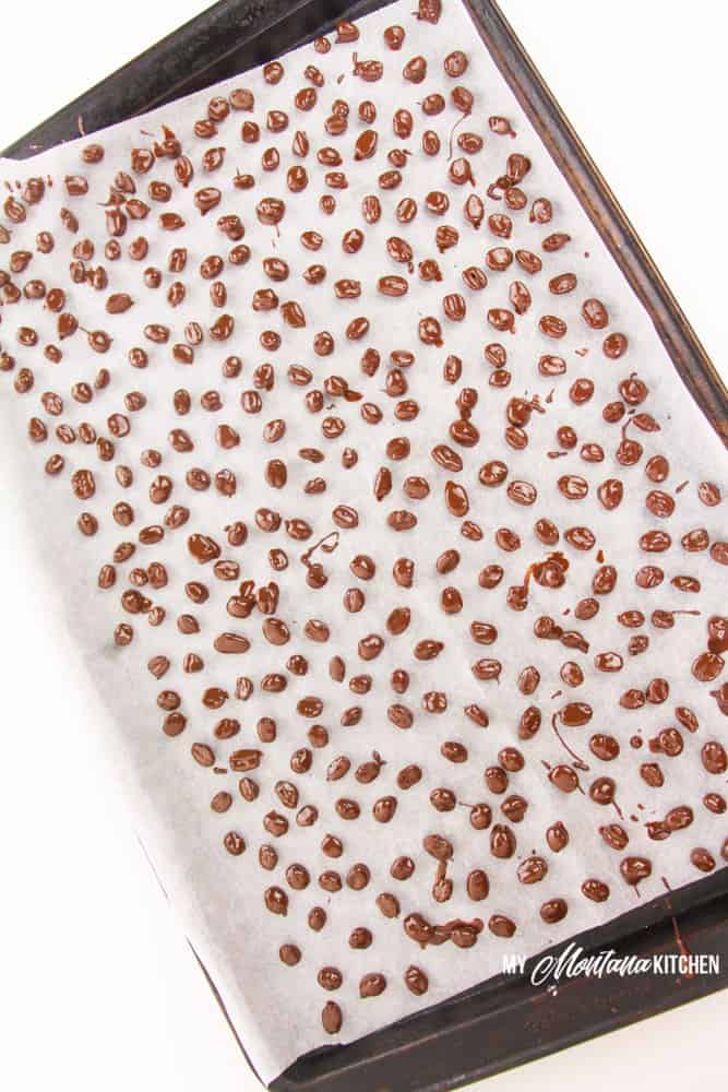 chocolate covered coffee beans on parchment lined baking sheet