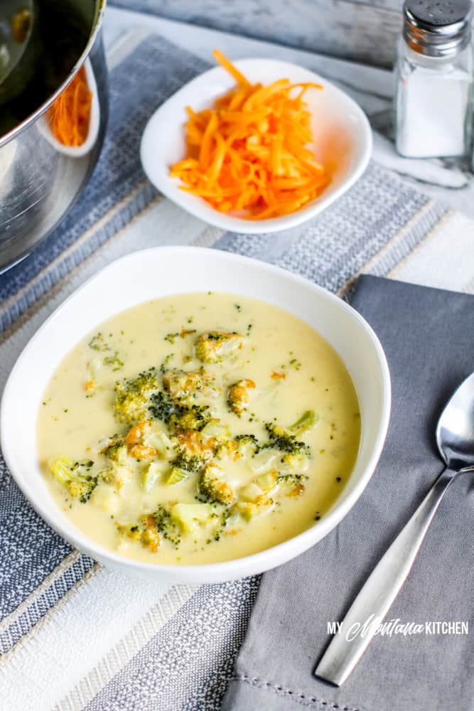 Image of low carb broccoli cheese soup with shredded cheese in the background