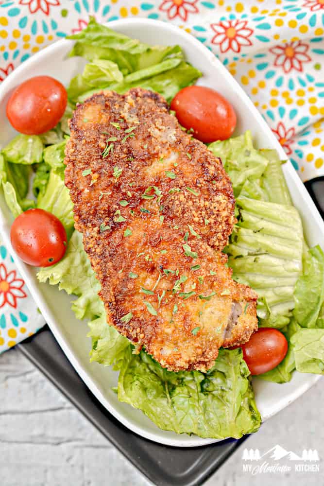 Parmesan crusted pork chop on lettuce with tomatoes