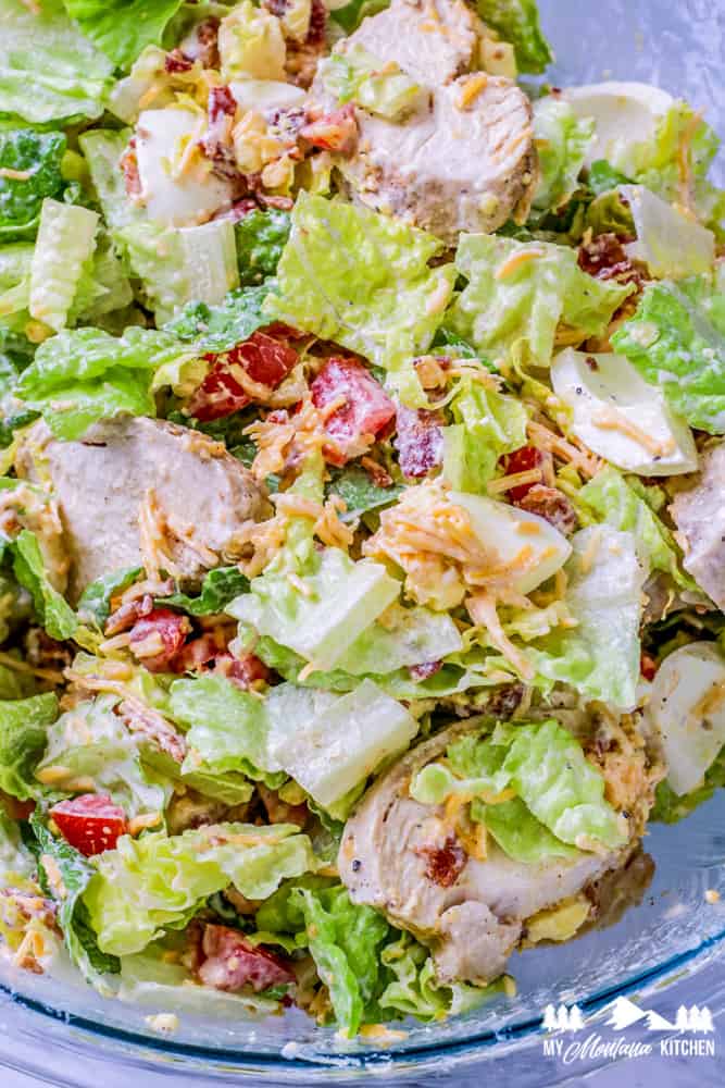 chicken cobb salad with dressing in glass bowl