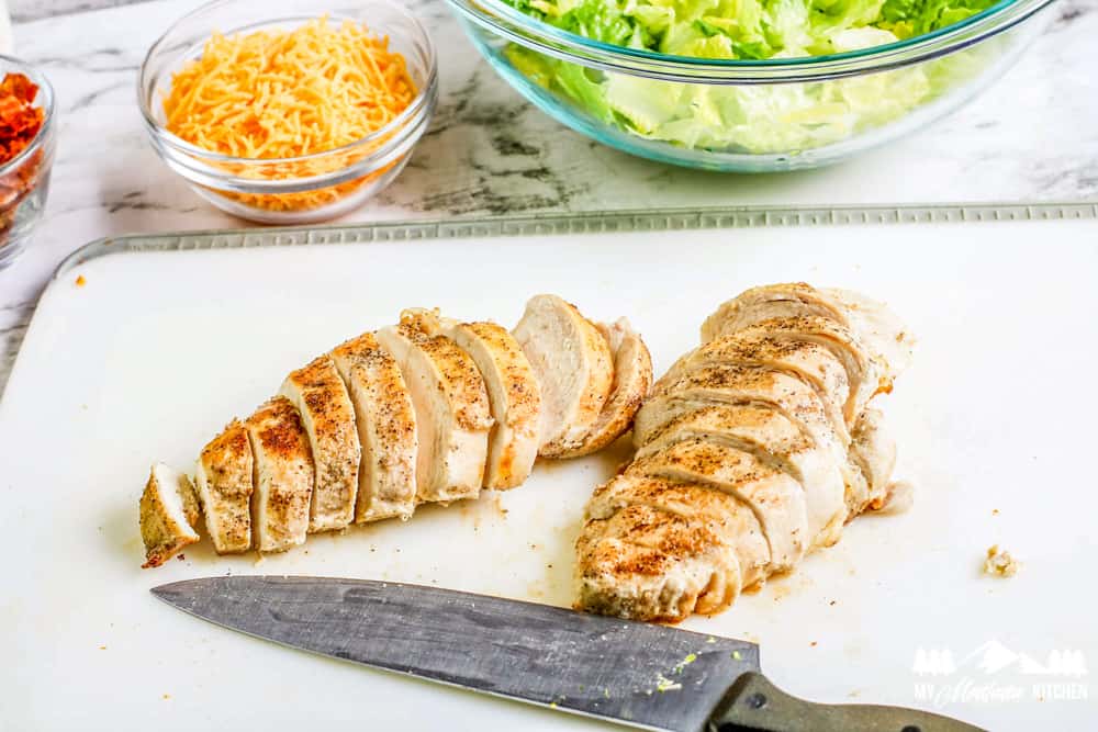 sliced grilled chicken on cutting board