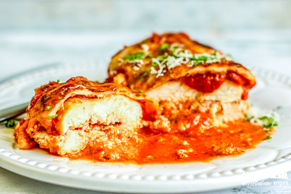 open baked lasagna stuffed chicken breast on white plate