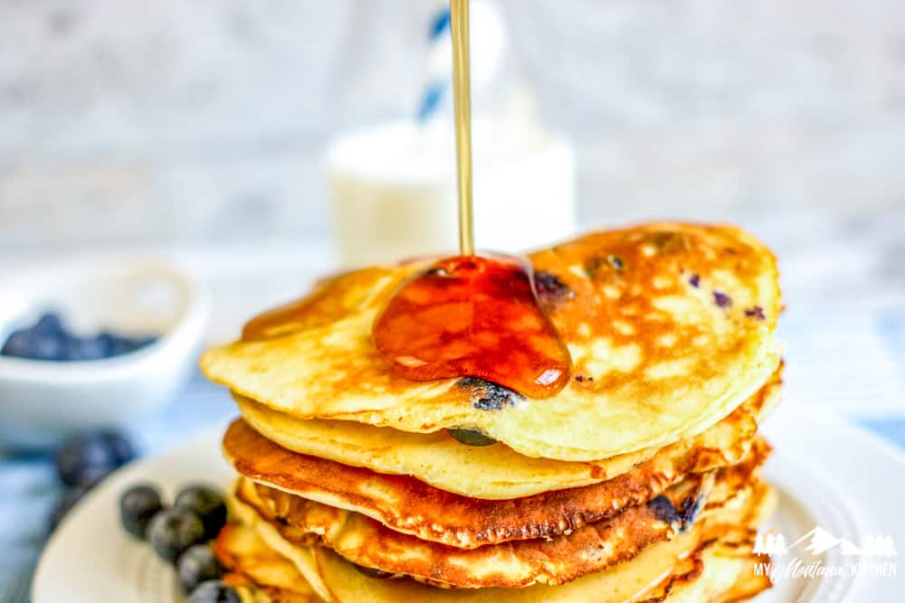 pouring syrup on blueberry pancakes
