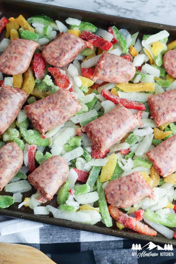 uncooked sausage and frozen peppers on baking sheet