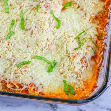 baked chicken parm casserole with basil in glass dish