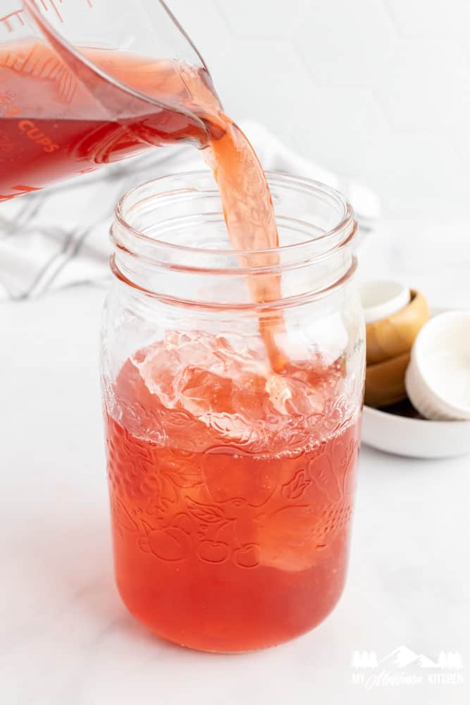 pitcher pouring tropical punch ggms into a mason jar