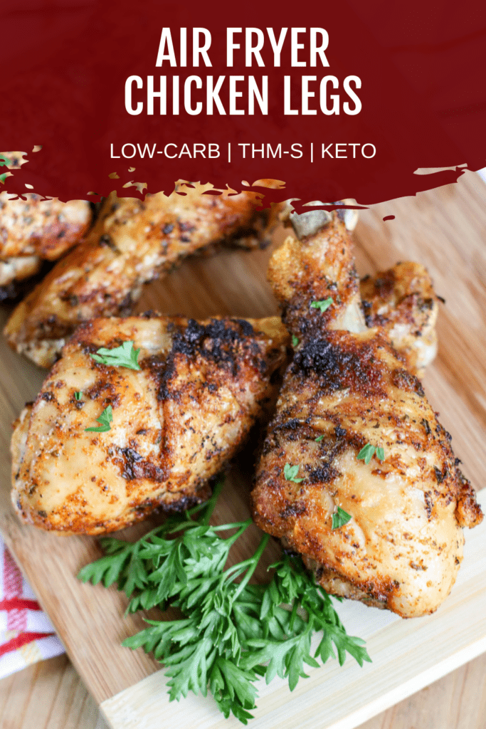 cooked chicken legs with green herbs on wooden cutting board