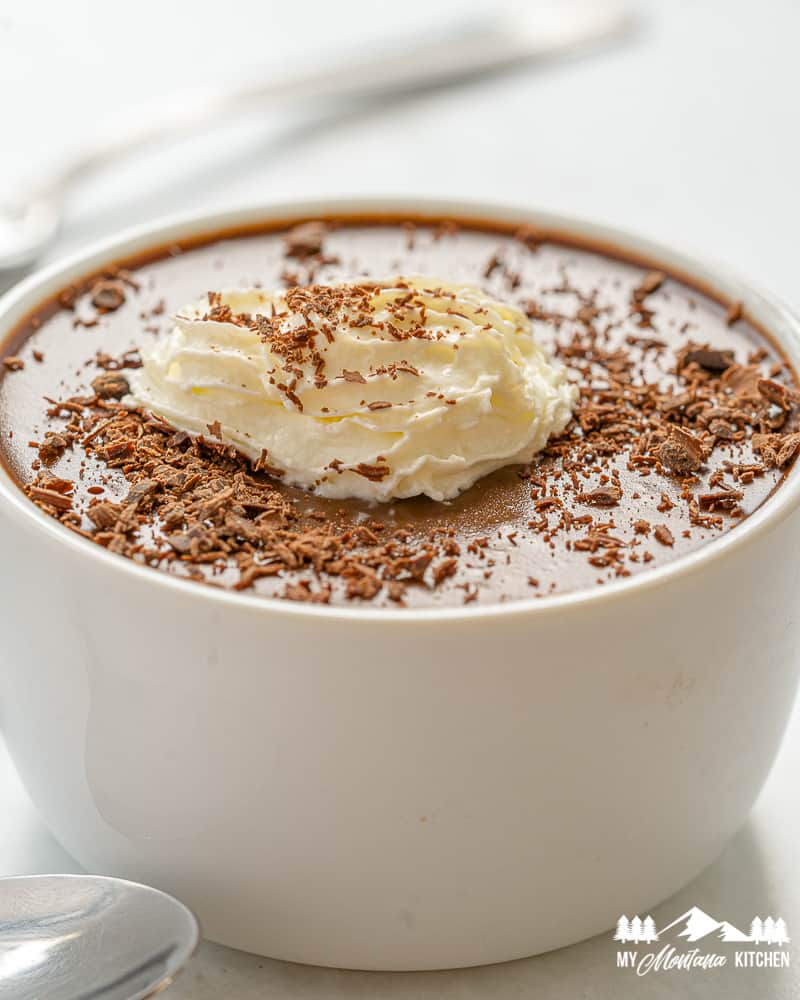 chocolate panna cotta in white ramekin with whipped cream and grated chocolate