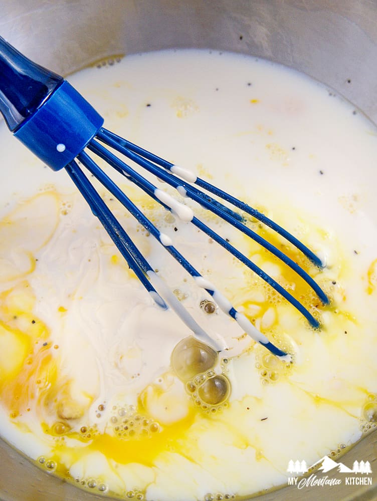 mixing eggs and cream in bowl with blue whisk