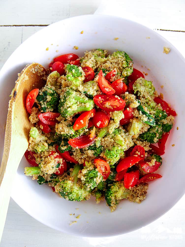 quinoa salad with broccoli in white bowl with wooden spoon