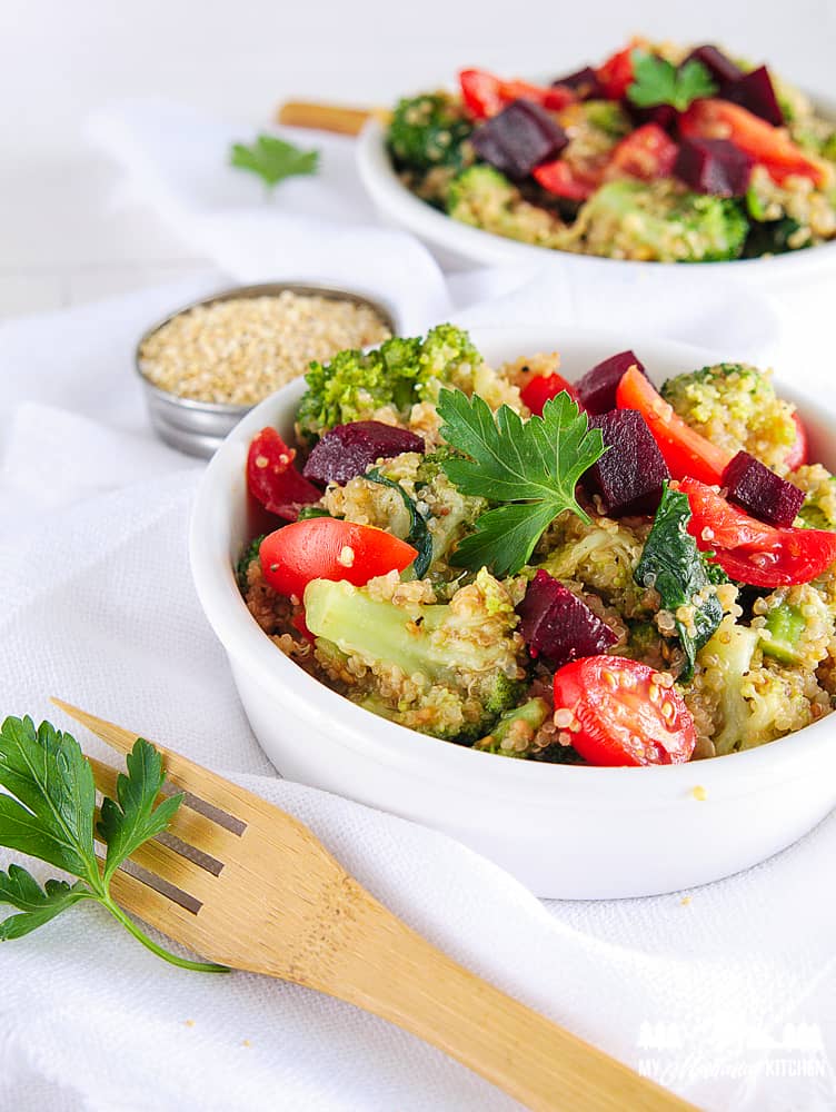 cooked quinoa salad with broccoli tomatoes and spinach in white bowl