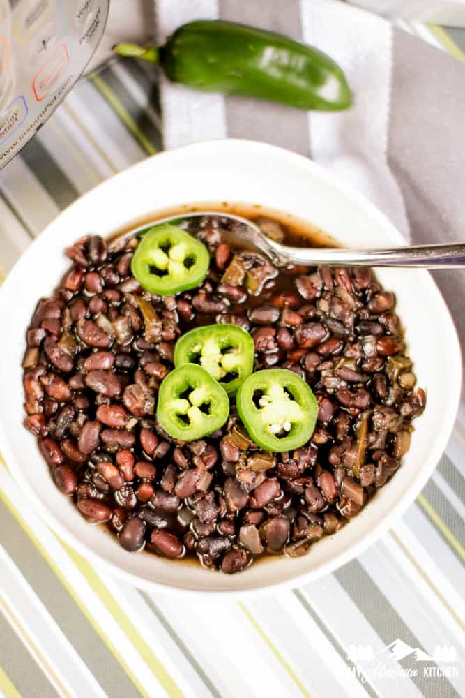 white bowl with black beans and fresh jalapeno slices