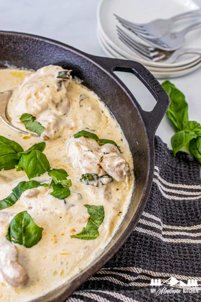 creamy sauce with basil and chicken thighs in iron skillet