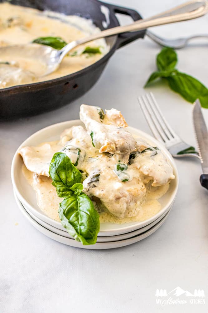 creamy basil chicken thighs on white plate