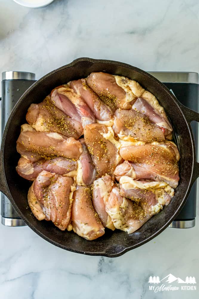 raw chicken thighs cooking in cast iron skillet