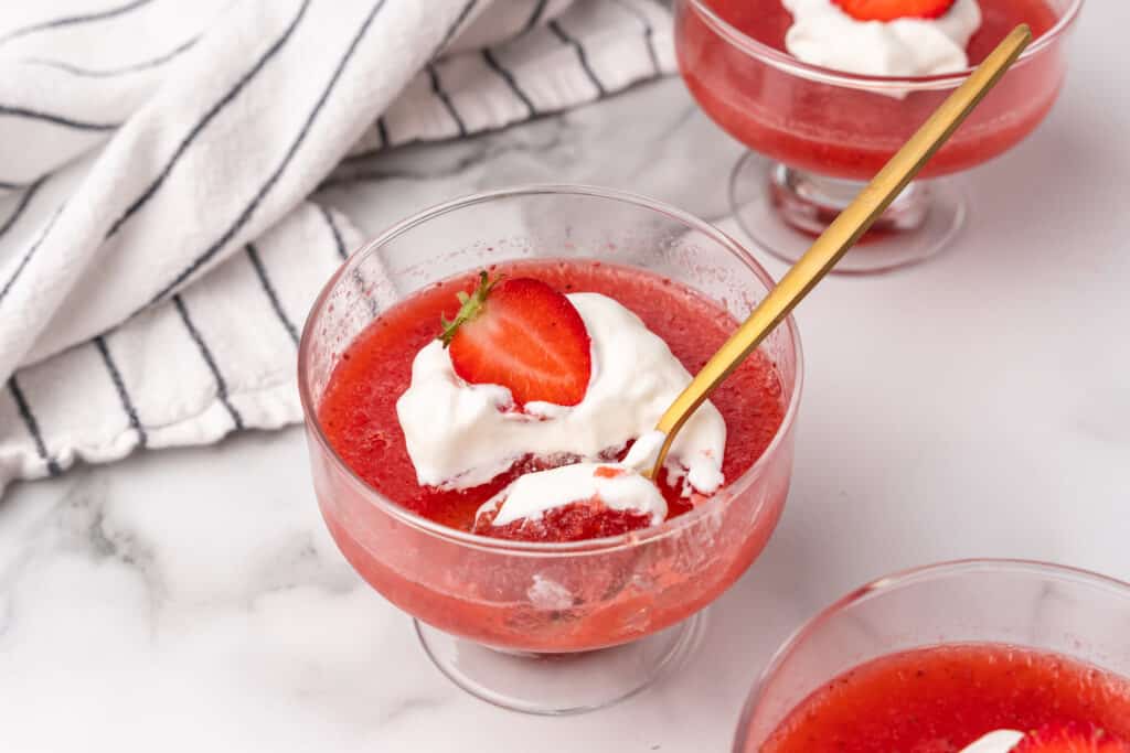 strawberry gelatin in glass cup with golden spoon