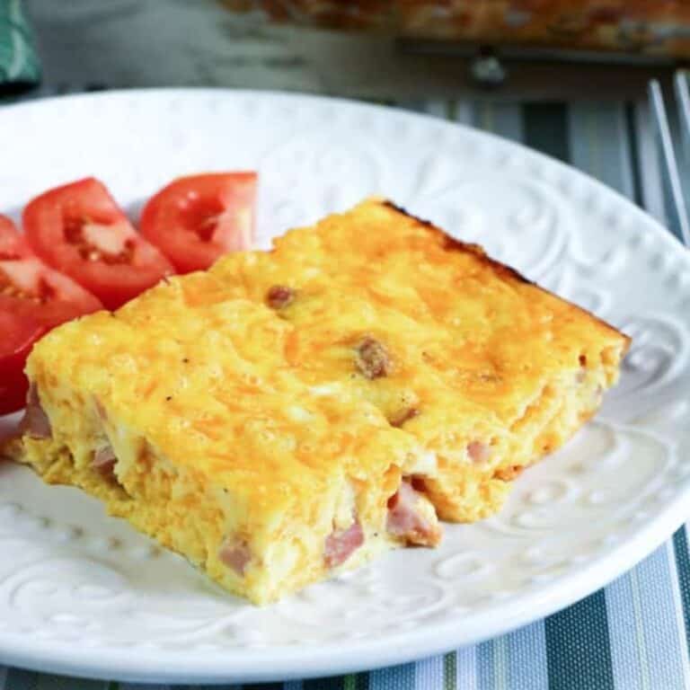 breakfast casserole on white place with tomatoes