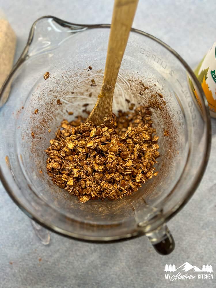 granola mixture with cocoa powder in glass mixing bowl