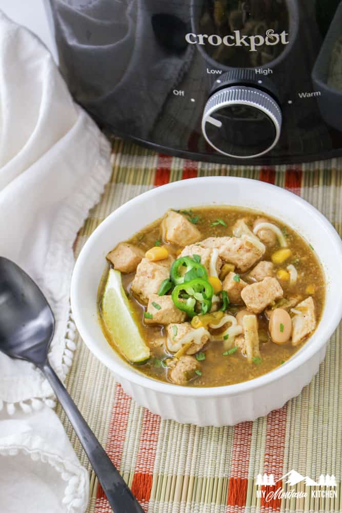 green chile chicken soup with lime and jalapeno in white dish
