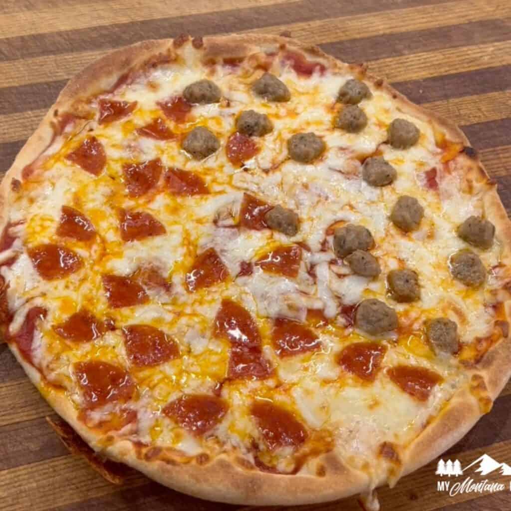 cooked sourdough pizza on wooden cutting board