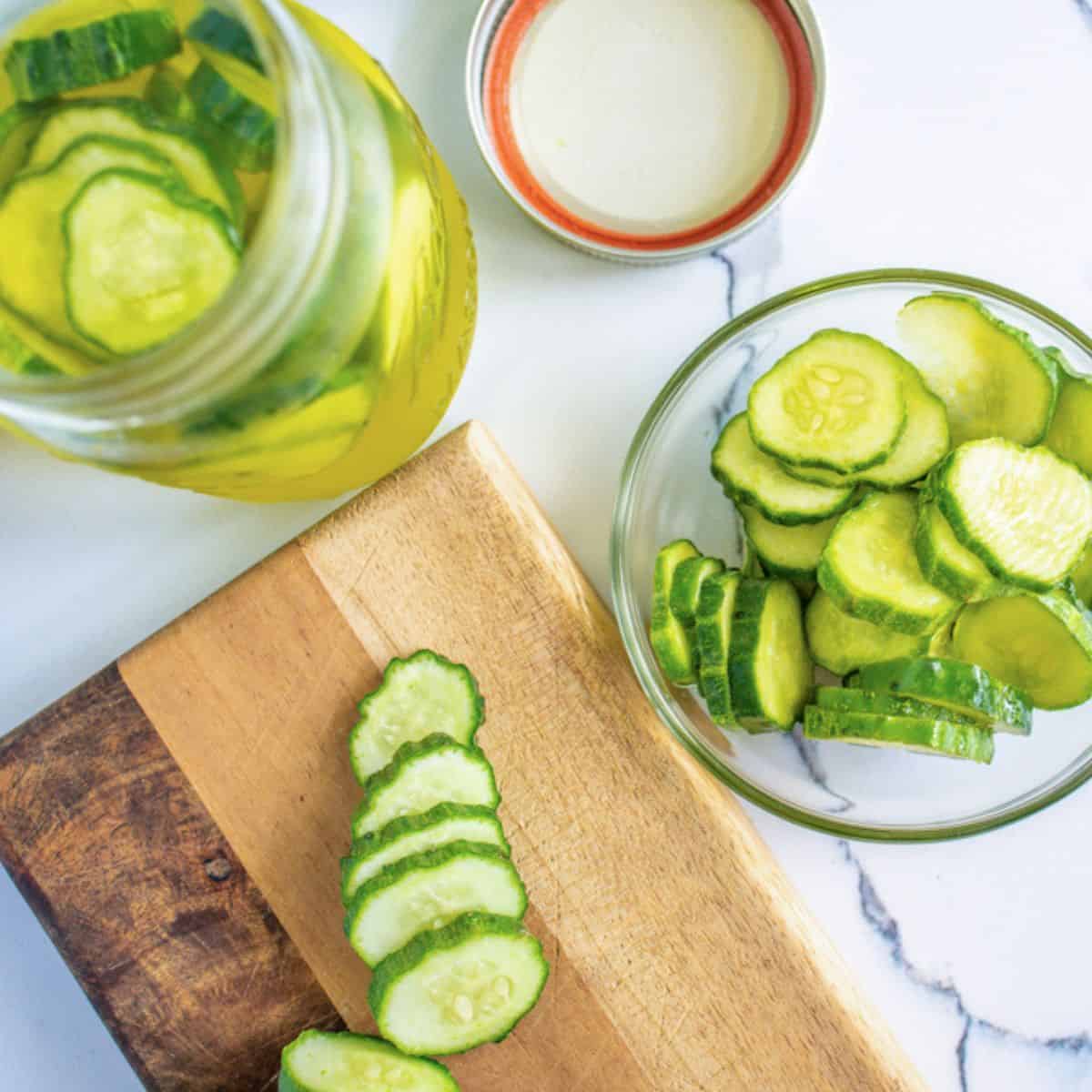 sliced cucumbers on cutting board and pickles in mason jar