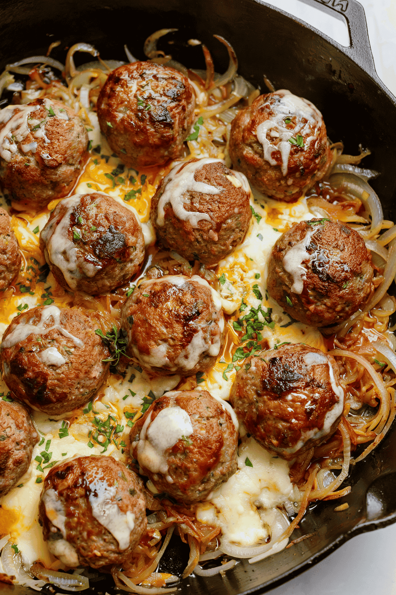 french onion meatballs with onions and cheese in skillet