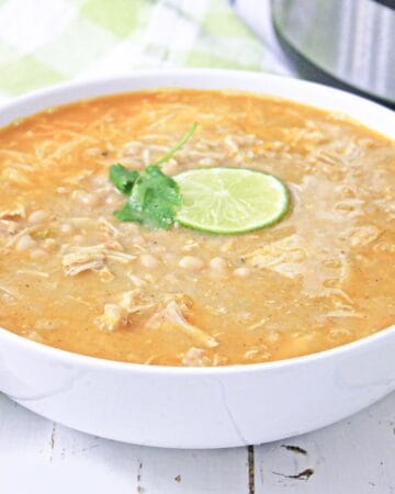 white chicken chili in white bowl with lime and cilantro