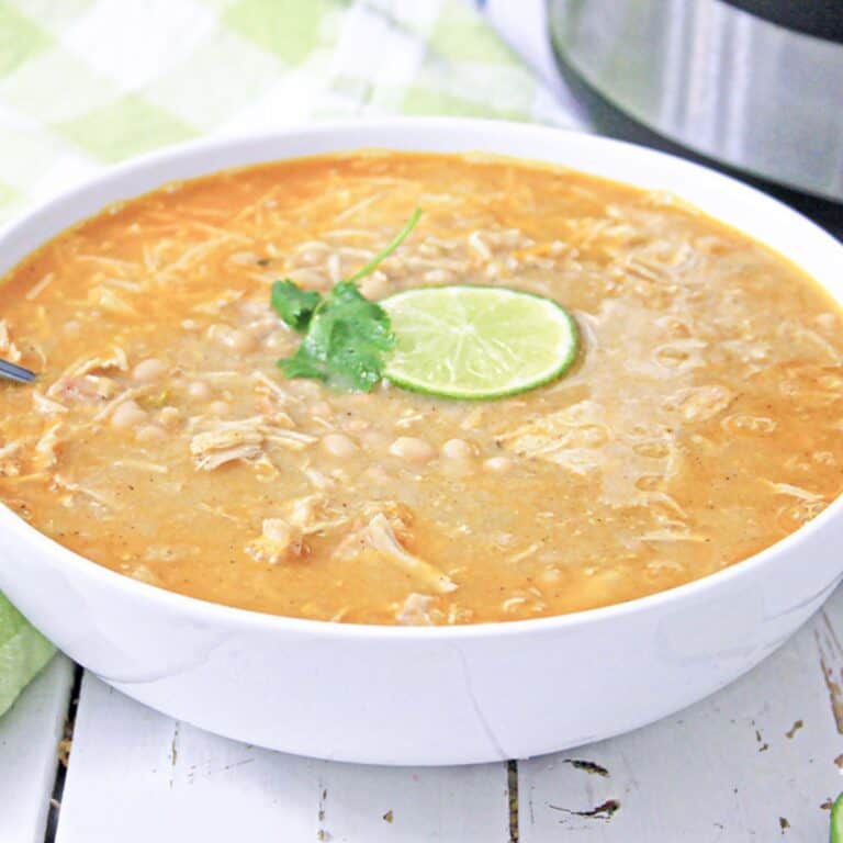 white chicken chili in white bowl with lime and cilantro