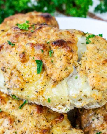 Juicy roasted Greek yogurt marinated chicken thighs, stacked on a plate with a golden brown, crispy crust.