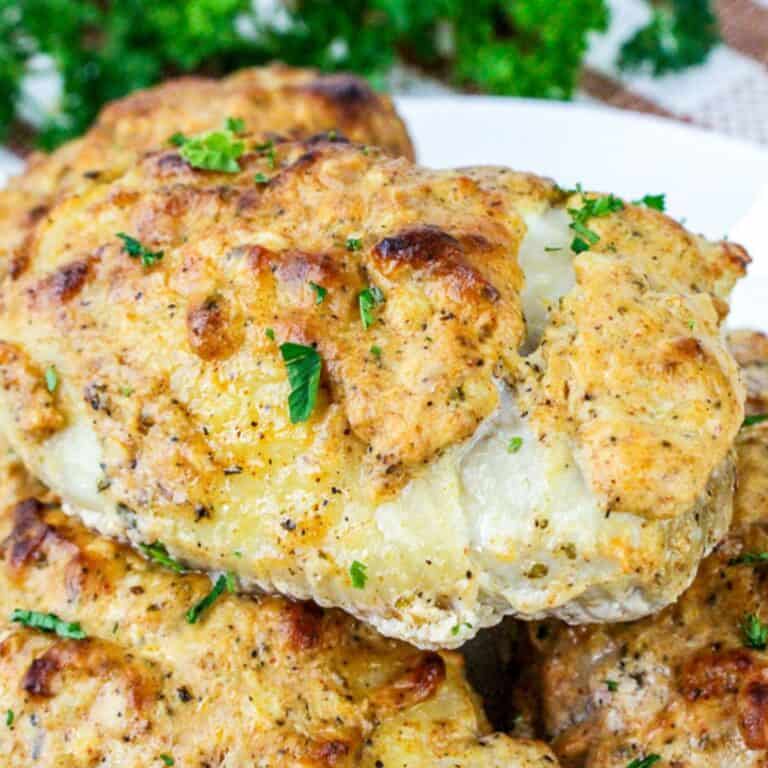 Juicy roasted Greek yogurt marinated chicken thighs, stacked on a plate with a golden brown, crispy crust.