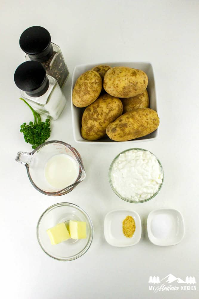 Flat lay of ingredients for cottage cheese mashed potatoes, including potatoes, cottage cheese, butter, milk, garlic powder, salt, and pepper.