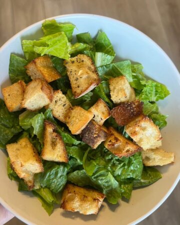 croutons on lettuce in white bowl
