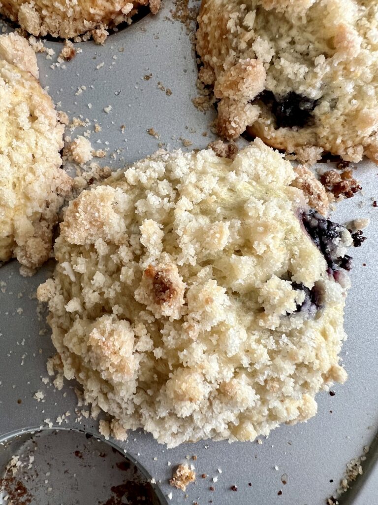 close up of sourdough blueberry muffin with crunchy crumb topping