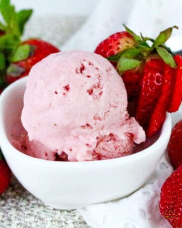 Scoop of strawberry cottage cheese ice cream in white bowl with fresh strawberries