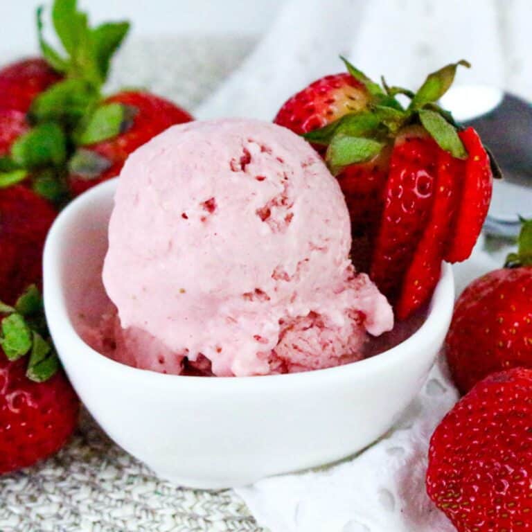 Scoop of strawberry cottage cheese ice cream in white bowl with fresh strawberries