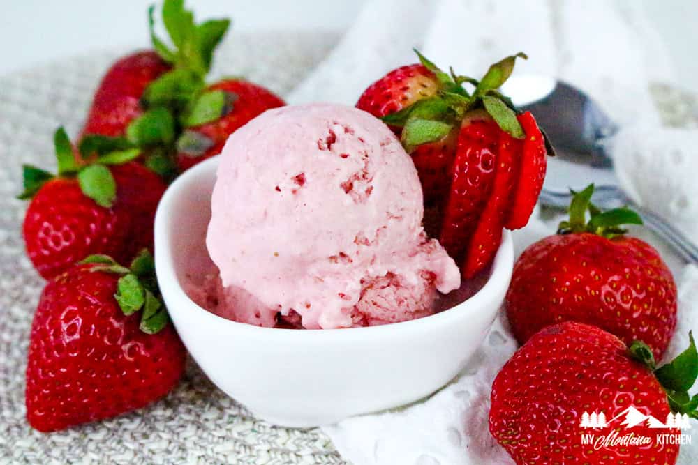 Full bowl of strawberry cottage cheese ice cream with strawberries on side