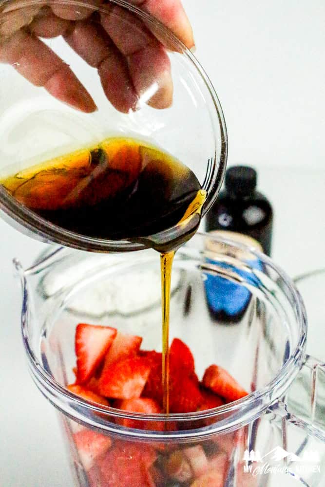 Pouring syrup over strawberries in blender