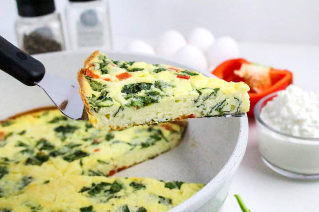 Close-up of a slice of spinach and cottage cheese frittata being served from a skillet