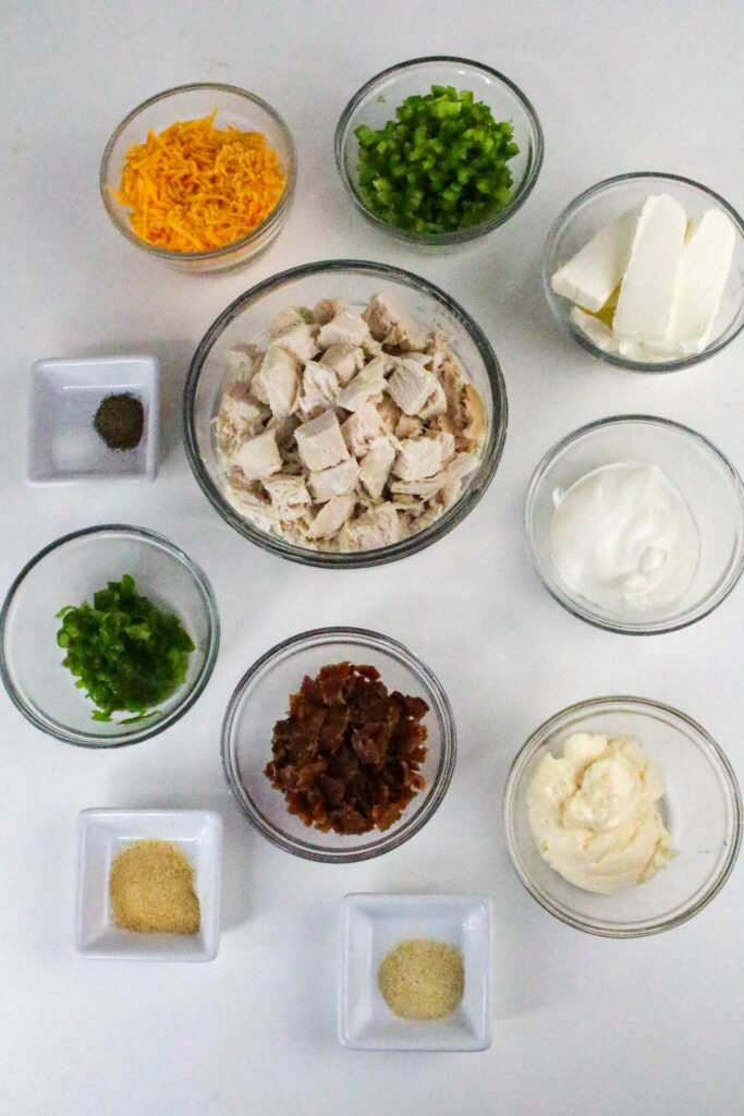 Overhead shot of prepped ingredients for jalapeño popper chicken salad laid out in separate bowls.