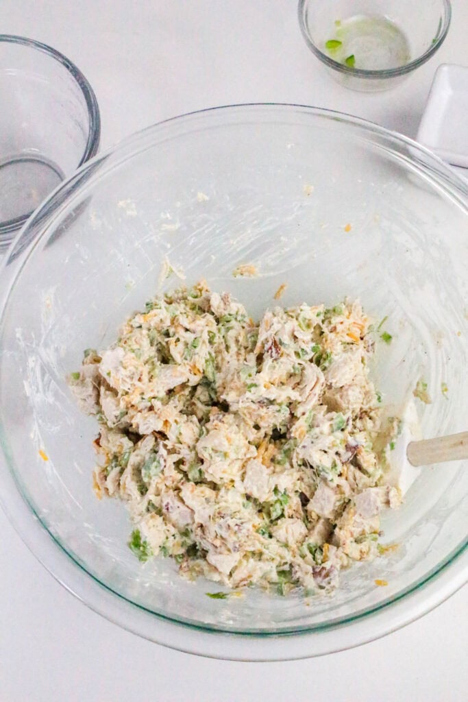 A large glass bowl filled with freshly mixed jalapeño popper chicken salad ready to chill.