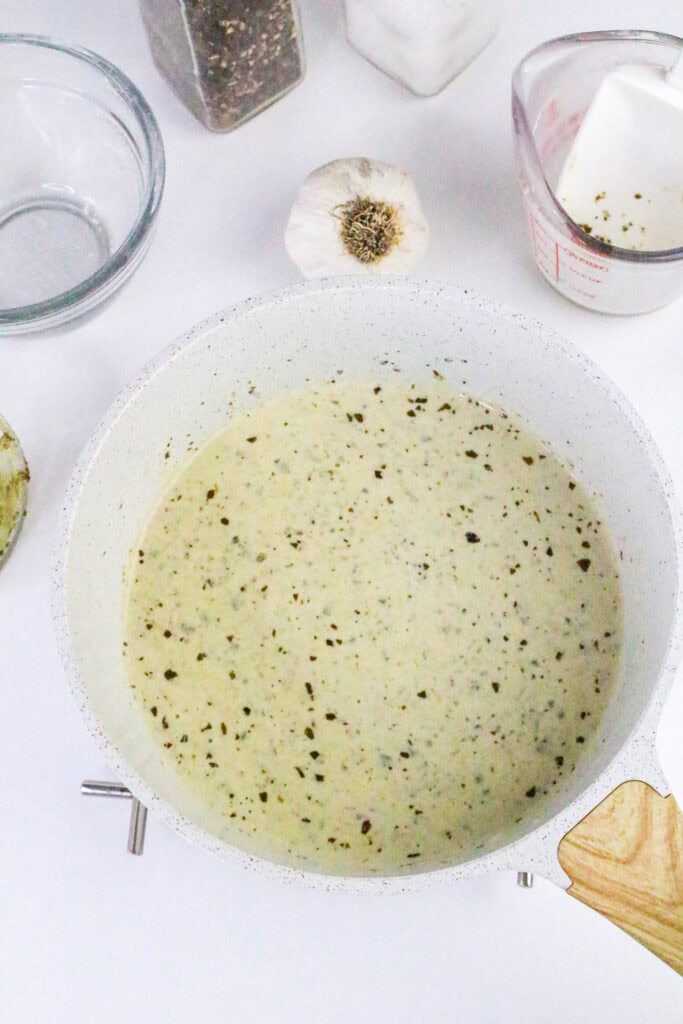 Finished low carb pesto Alfredo sauce in a skillet, smooth and speckled with basil for a rich, creamy texture.