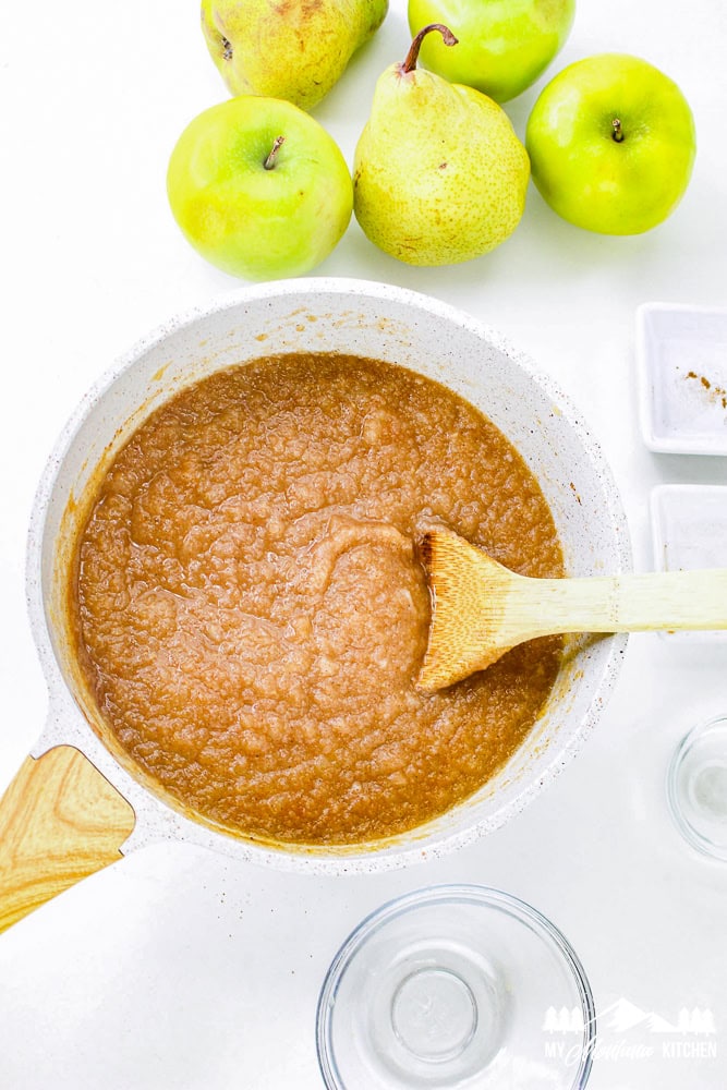 Smooth, fully cooked apple pear sauce in a white pot with a wooden spoon ready for serving.
